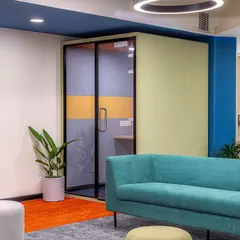 A vibrant acoustic pod adds a pop of color and high functionality to this breakout area. It provides a soundproof space for private calls without having to leave the collaborative zone.