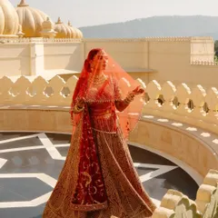 Bride Shree looking ethereal in her red Tarun Tahiliani wedding lehenga. The sheer veil and the stunning backdrop create a truly magical moment.