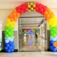 A vibrant rainbow balloon arch at the entrance of a banquet hall, perfect for a colorful Cocomelon or carnival-themed party.