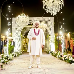 The groom stands at the entrance of the beautifully decorated wedding venue, looking regal and ready for his grand entry.