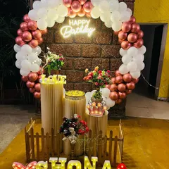 A beautiful ring decoration with rose gold and white balloons against a brick wall, personalized with light-up letters.