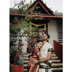 A moment of pure joy and comfort. This portrait captures the couple in a relaxed embrace against a traditional backdrop, their happy expressions telling the story of their love.