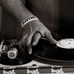 A close-up of my hand on the vinyl, wearing the artist wristband. This shot captures the tactile nature of DJing with records, a craft I am deeply passionate about.