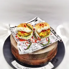 Another angle of my hyper-realistic Vada Pav cake, this time on a wood-textured cake stand. It's a butterscotch cake inside, but it looks just like the real spicy snack.