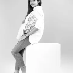 A relaxed and minimalist portrait in black and white. The mother-to-be is styled in a simple white shirt and jeans, creating a timeless and natural look that feels effortlessly beautiful.