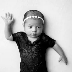 An awake baby waving at the camera. In black and white, this simple gesture becomes a charming and artistic portrait full of personality.