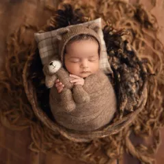 So cozy and cute. This newborn is swaddled in brown wool with a matching teddy bear hat and a tiny stuffed friend, perfect for a rustic-themed baby boy photoshoot.