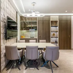The dining area is anchored by a 3D-paneled wall, adding texture and depth. We integrated a bar nook and display shelves with backlighting, making it an elegant and functional space for entertaining.