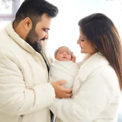 Welcoming a new baby is a magical time. This studio portrait captures the tender moment between new parents as they lovingly gaze at their sleeping newborn.