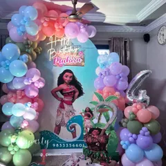 We created this tropical Moana theme for a 4th birthday party. The setup includes a custom backdrop with Moana, a colorful balloon arch, character props of Maui and Pua, and a number '4' balloon column.