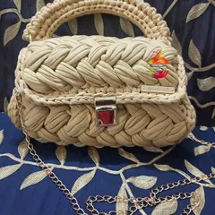 A detailed look at the beige version of my braided handbag. The light color highlights the intricate texture of the crochet work, and it sits beautifully against a patterned background.