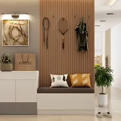 A stylish foyer design with a white cabinet and a cushioned bench. The slatted wood wall panel includes hooks for hanging coats and accessories.