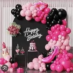 A chic makeup-themed birthday party. The black backdrop is framed by a pink and black balloon arch, with foil balloons shaped like lipstick and high heels, and a dessert table with themed treats.