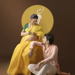 A beautiful moment between the couple during their traditional Marathi maternity shoot. The symbol for 'Maa' (Mother) projected behind them adds a layer of deep cultural meaning.
