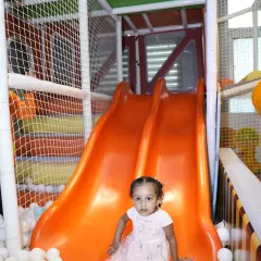 A little one sits at the bottom of our dual orange slides, ready to climb up and go again.