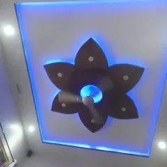 This PVC ceiling features a beautiful flower-shaped design around the fan. The cool blue backlighting creates a calming and modern ambiance in the room.