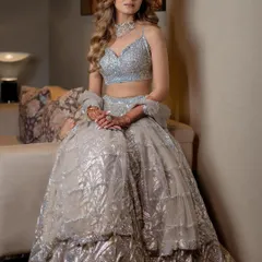 A seated portrait showing the intricate details of the reception outfit and the soft, shimmering makeup.