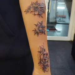 This client wanted to cover scars on her arm. We designed this beautiful floral piece that flows along the arm, turning the scars into a garden of fine-line flowers.