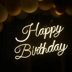 A detailed shot of the "Happy Birthday" neon sign, a popular decoration for modern parties. We focus on capturing the mood and ambiance.