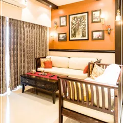 A living room with a Durga-inspired gallery wall against a terracotta-colored accent wall, channeling devotional energy.