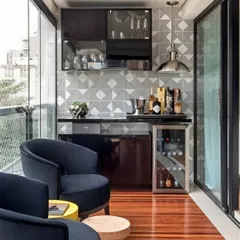 This sophisticated setup features a sleek, dark-toned bar with a dedicated wine cooler. The geometric tile backsplash and industrial-style pendant light add a modern, chic vibe, complemented by comfortable club chairs for a lounge-like feel.