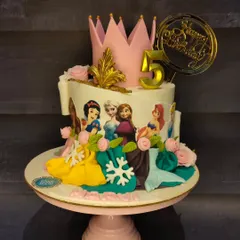 A dream cake for a Disney Princess fan. This design features beautiful illustrations of various princesses, with sculpted dresses and a royal crown on top, perfect for a 5th birthday.