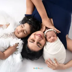 A creative overhead shot of a mother with her two daughters. This pose beautifully showcases the connection between a mom, her older child, and the new baby.