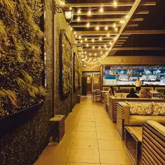 I designed this rooftop cafe to be an inviting evening destination. The combination of a full-length vertical garden, warm string lights under a pergola, and comfortable slatted wood seating creates a cozy and vibrant ambiance for guests.