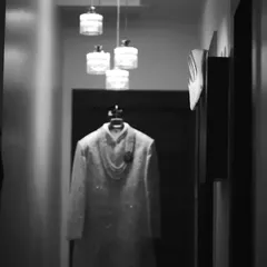A black and white, artistic shot of the groom's wedding attire. The moody lighting and composition give this detail shot a sophisticated and timeless feel.