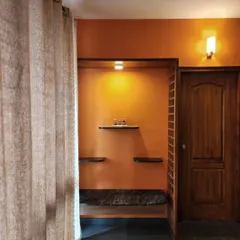 A custom-designed foyer nook with a built-in bench and shelving. The warm orange wall and wood detailing create a welcoming entryway, demonstrating how small interventions can have a big impact.
