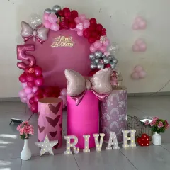 A chic and modern pink-themed party for Rivah's 5th birthday, complete with a 'Happy Birthday' neon sign and bow-shaped foil balloons.