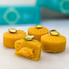 Our Mango Cake Mithai, featuring a rich mango-flavored filling and garnished with a pistachio slice. It's a taste of summer in a bite-sized treat.