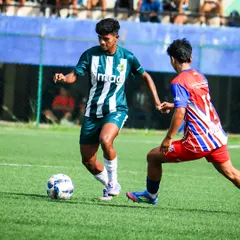 A player in our striped kit skillfully dribbles past an opponent, demonstrating the high level of technical ability in our youth leagues.