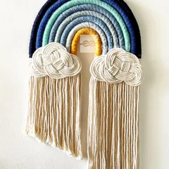 A close-up of one of my rainbow wall hangings in a cool-toned palette. This piece features shades of blue and a pop of yellow, with detailed cloud knots and a long fringe.