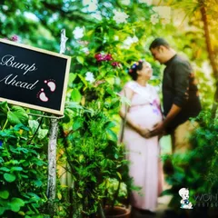 Using creative props like this "Bump Ahead" sign adds a fun and whimsical element to the photoshoot. It creates a playful memory while the couple shares a moment in the background.