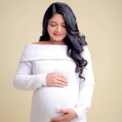 A serene and simple portrait in a comfortable white knit dress. This minimalist approach focuses on the quiet joy and beauty of pregnancy.