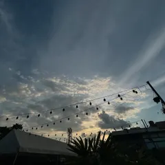 The beautiful evening sky over our rooftop venue, with string lights silhouetted against the clouds, promising a magical night ahead.