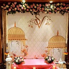 A lovely backdrop for a home ceremony with an SV monogram. The design includes illustrations of traditional domes and is paired with a low seating arrangement on a bed of rose petals.