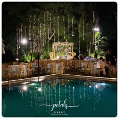 A magical poolside reception at The Lalit Ashok Bangalore. The fairy lights hanging from the trees are reflected in the water, creating a dazzling and romantic atmosphere for the celebration.