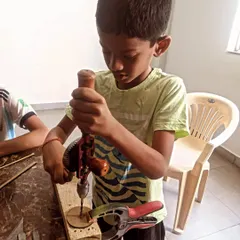 This young craftsman is concentrating hard as he uses a hand drill. These tools are excellent for developing motor skills and strength.