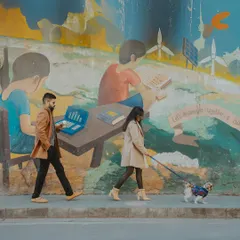A couple walks their dog past a vibrant street mural, blending their everyday life into their pre-wedding photoshoot. We love incorporating personal elements into our sessions.