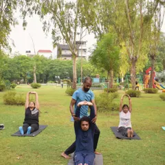 I also take our practice outdoors. Here, I'm assisting a client in an outdoor yoga session, helping her achieve a deeper stretch and proper alignment while enjoying the fresh air.
