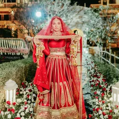 A stunning bridal portrait in Pushkar, with the bride lifting her veil against the backdrop of the beautifully lit palace at night.