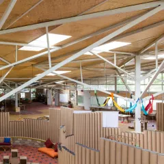 The Atelier school's interior is a prime example of designing for disassembly. The paper tube partitions and bolted steel structure were chosen specifically so they can be easily taken apart and reused in the future, preventing demolition waste.