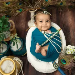 A sweet smile from a little one dressed for Janmashtami. I use soft lighting and props like pearl necklaces and peacock feathers to create a rich, detailed portrait.