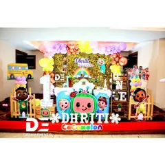 A dazzling Cocomelon first birthday for Dhriti. The setup includes a gold sequin backdrop, character cutouts, and a large 'ONE' sign, blending the fun of the cartoon with a touch of glamour.