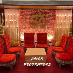 For this indoor 'vidhi mandap', I created a warm and inviting atmosphere. The backdrop is a wall of soft pink flowers featuring a golden 'Om' symbol, surrounded by glowing candle stands and traditional red seating.