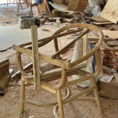 The raw wooden frame of a chair during the early stages of construction. You can see the curved components and joinery before sanding and finishing, a testament to the solid wood construction.