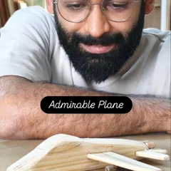 A student admiring the wooden airplane he just finished. There's a special kind of pride that comes from creating a toy with your own hands.