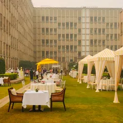 A sunny and cheerful brunch setup on a lush green lawn at The Lodhi, Delhi. The yellow and white striped cabanas provide a chic, resort-like feel for a relaxed daytime event.